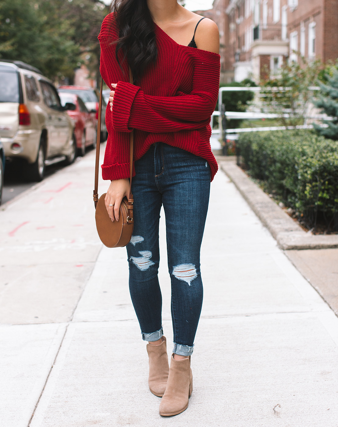 Trendy ripped denim jeans with cute red sweater and black leather belt.